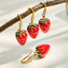 Red strawberry earrings displayed in a lifestyle jewelry setting