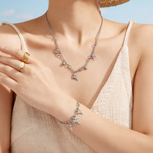 Model styling a gold reindeer necklace and matching bracelet with crossed arms