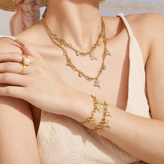 Model styling a gold reindeer necklace with the matching deer charm bracelet