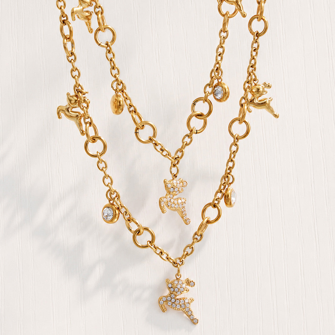 Close-up of gold reindeer necklace charms and clear zircon details on a light background