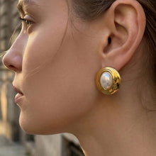 Side view of gold resin dome stud earrings worn on the earlobe