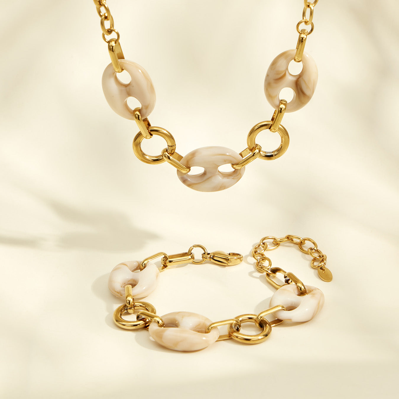 Gold resin link necklace and bracelet arranged together on a neutral background