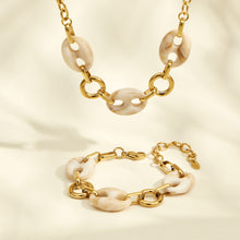 Gold resin link necklace and bracelet arranged together on a neutral background