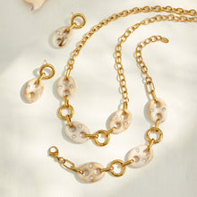 Cream resin link necklace and bracelet displayed together with gold chain details
