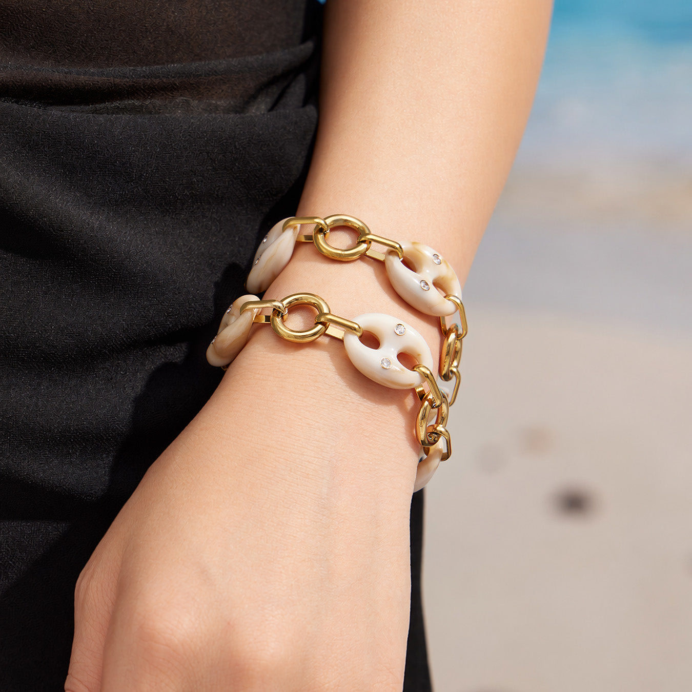 Model wearing a gold resin mariner link bracelet with a black sleeve