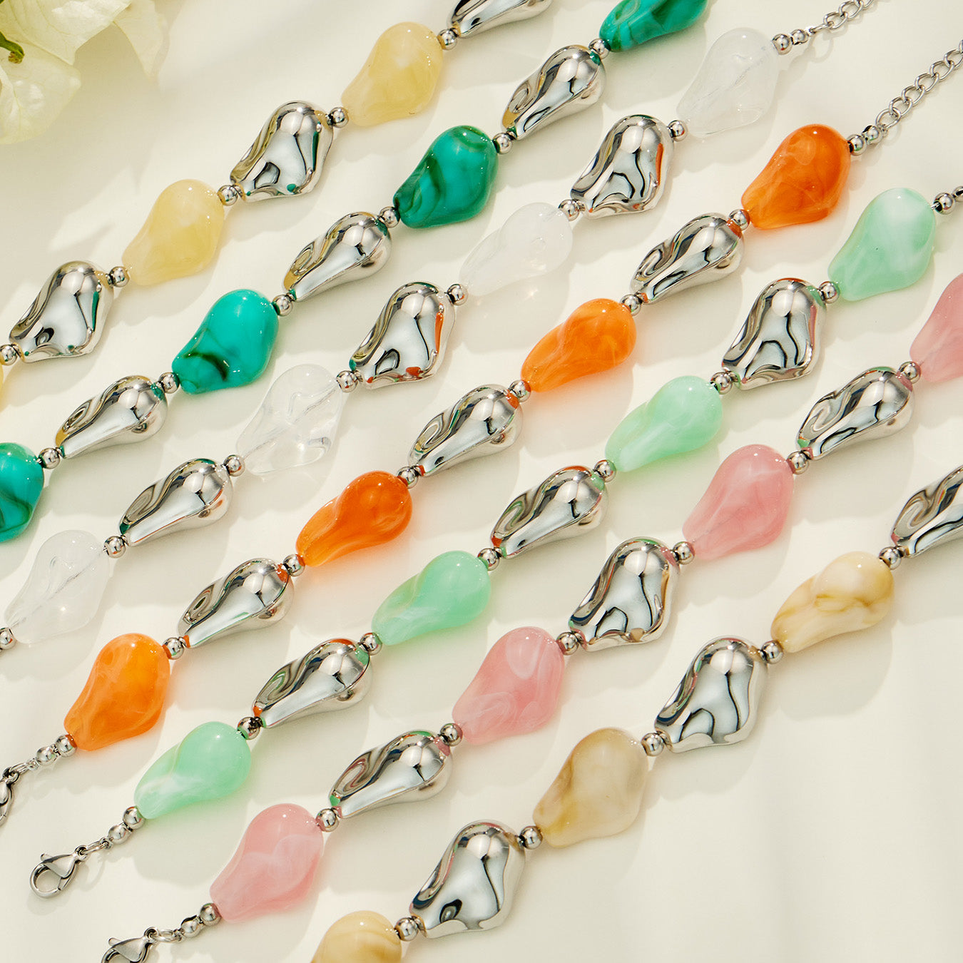 Flat lay of resin necklace and bracelet color options including green pink orange white and neutral tones