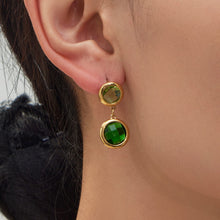 Close-up view of a model wearing a green glass stone drop earring made of nickel-free stainless steel.