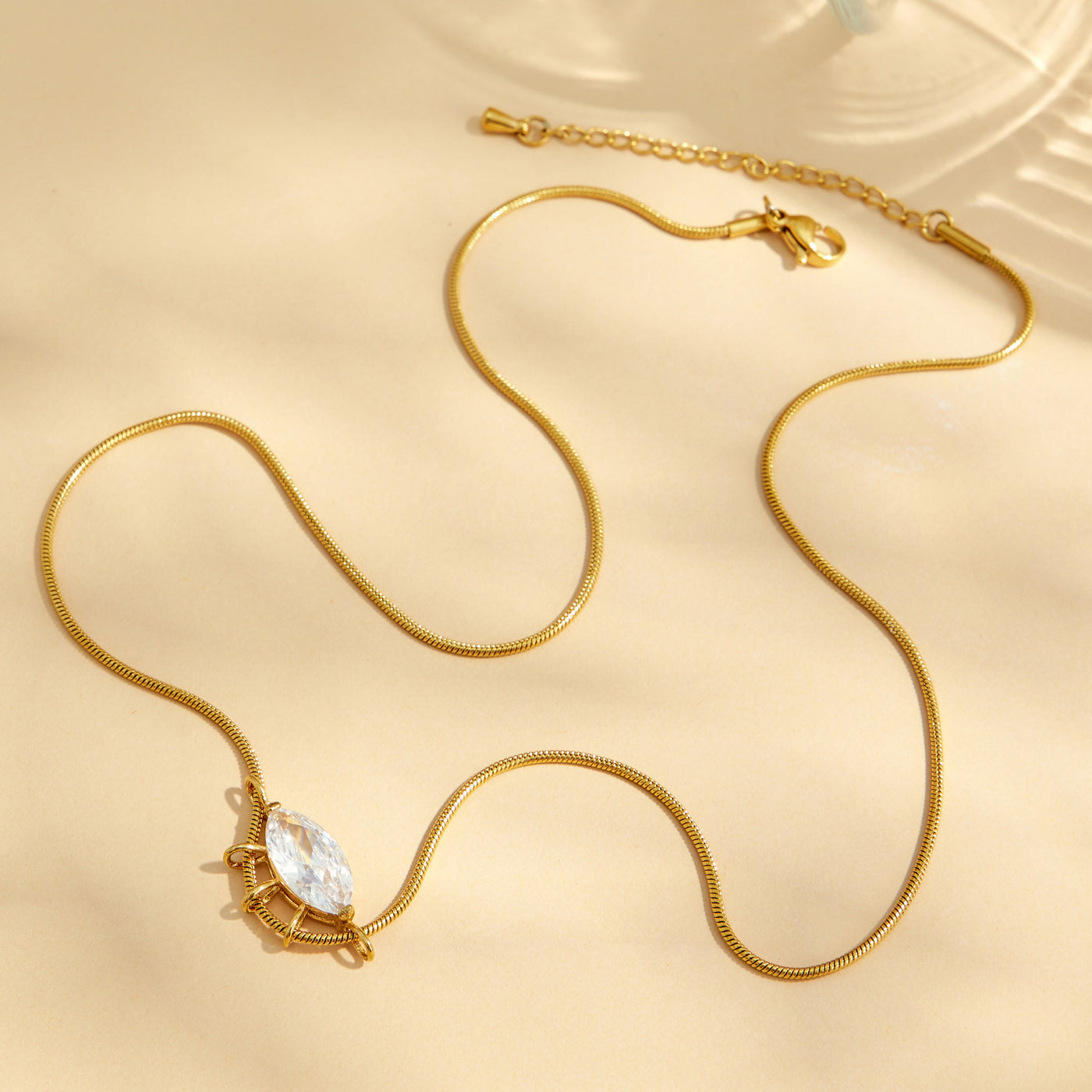 Full view of a round zircon pendant necklace with a fine gold-tone chain and extender
