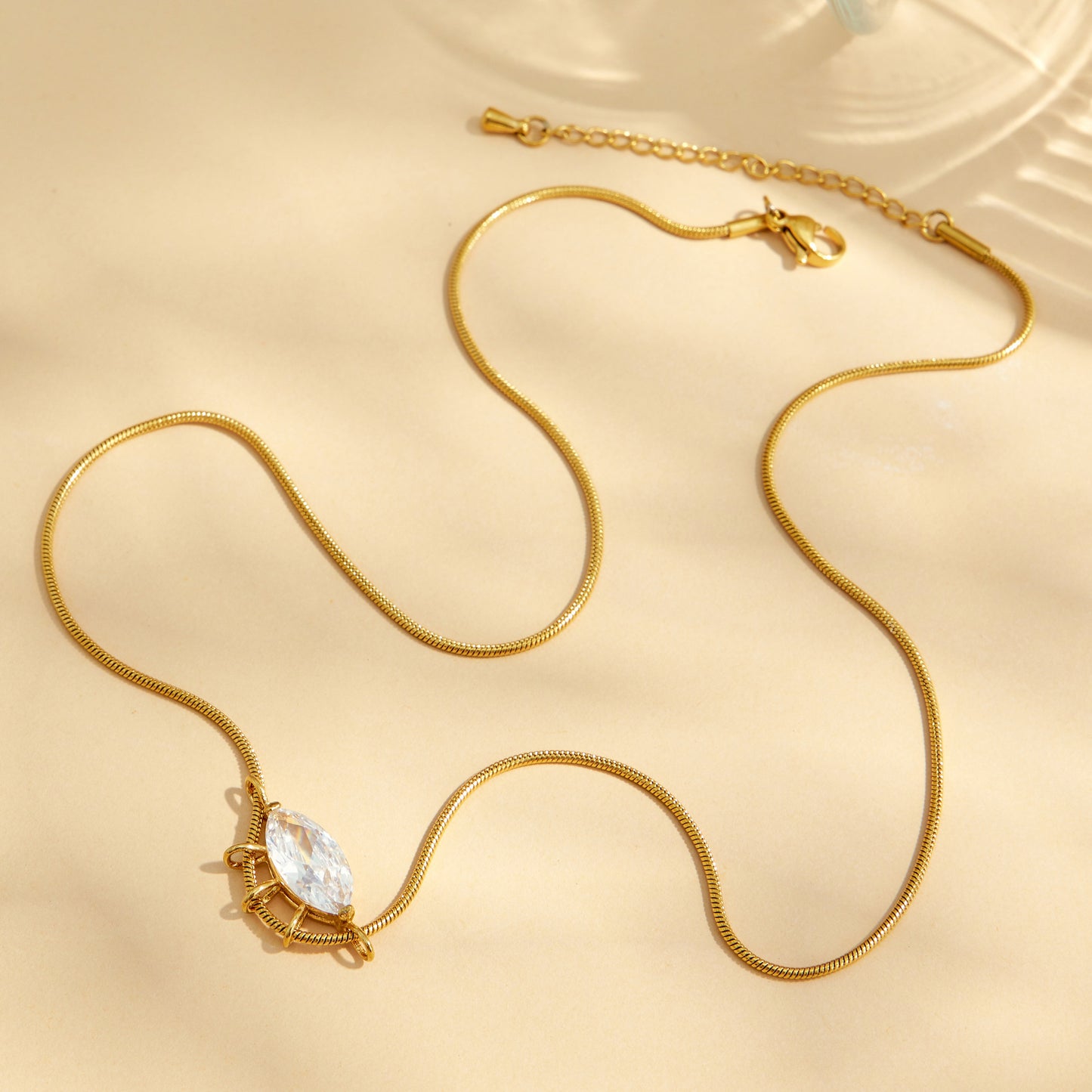 Full view of a round zircon pendant necklace with a fine gold-tone chain and extender