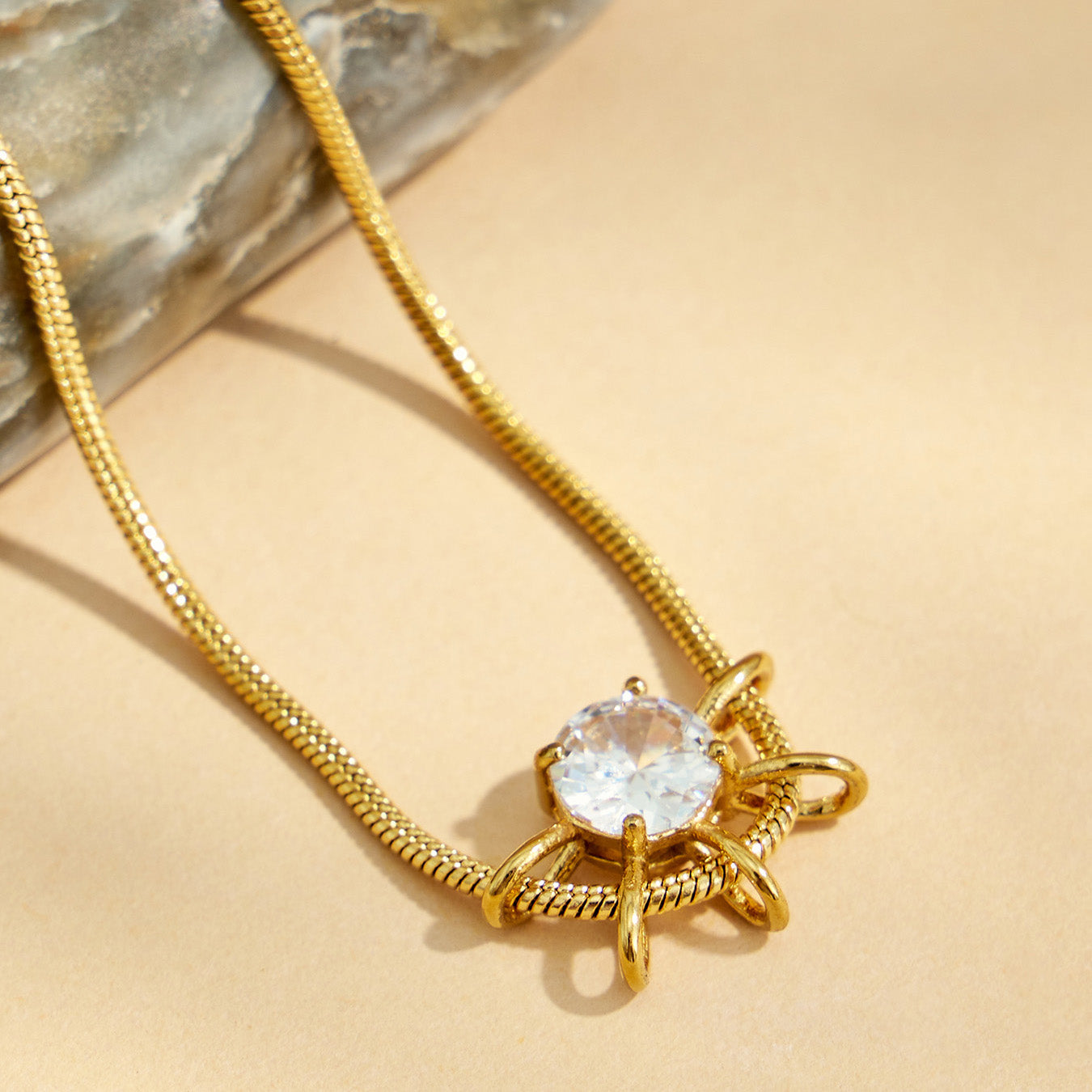 Close-up of a round zircon pendant with a gold-tone sunburst geometric setting