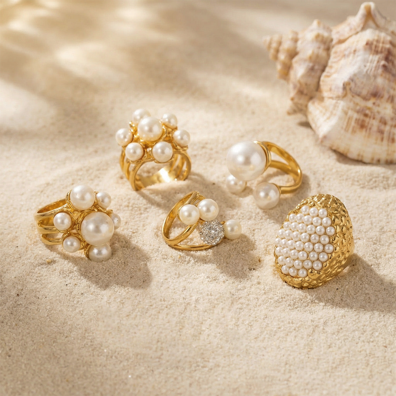 Sculptural gold faux pearl rings arranged on soft beige fabric