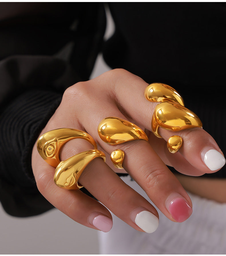 Gold-tone asymmetric open rings and cutout rings styled together on a model's hand