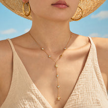 Gold-tone sea turtle Y necklace worn on model in summer resort styling