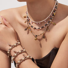 Model wearing a double-row shell pearl bracelet with layered beaded necklaces