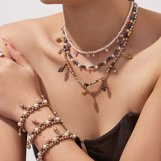 Model wearing a double-row shell pearl bracelet with layered beaded necklaces