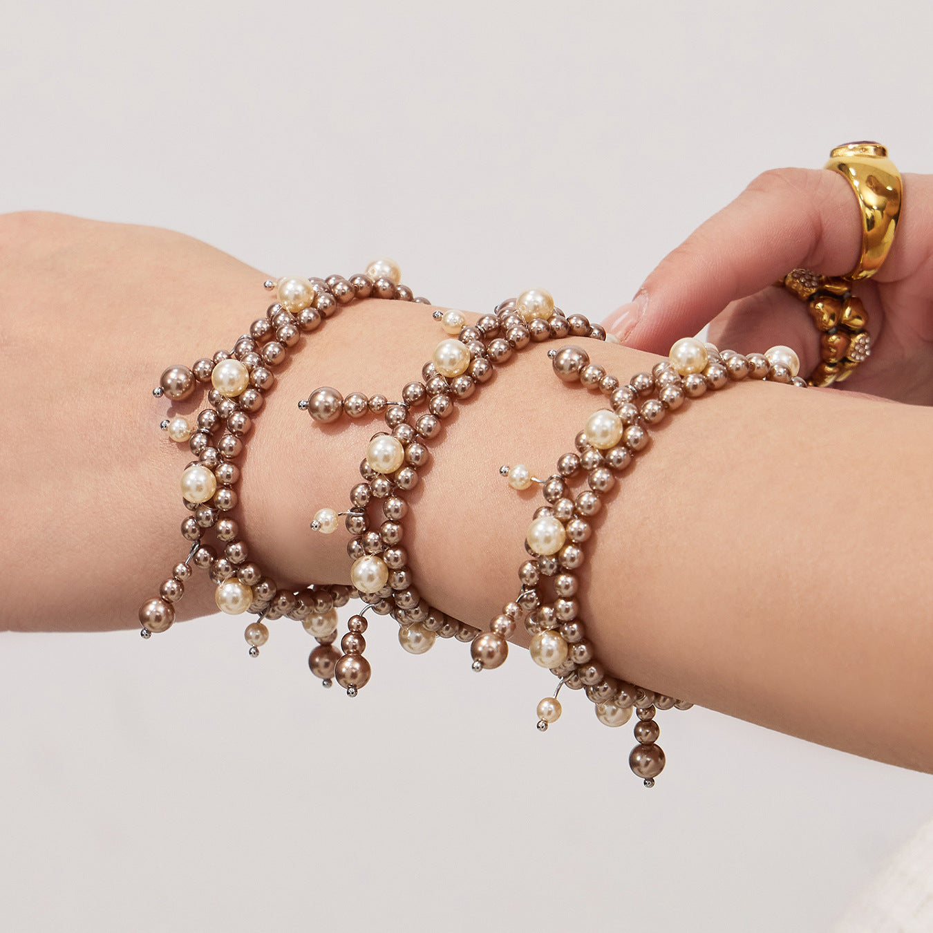 Close-up of a shell pearl tassel bracelet styled on a model wrist