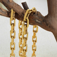 Close-up of a silver stainless steel chain necklace displayed on soft fabric