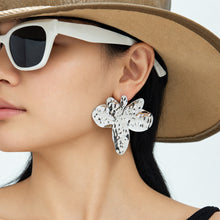 Steel-tone hammered flower earrings shown on model