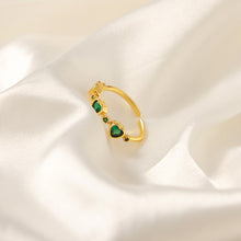 Single green heart zircon ring displayed upright on soft ivory satin