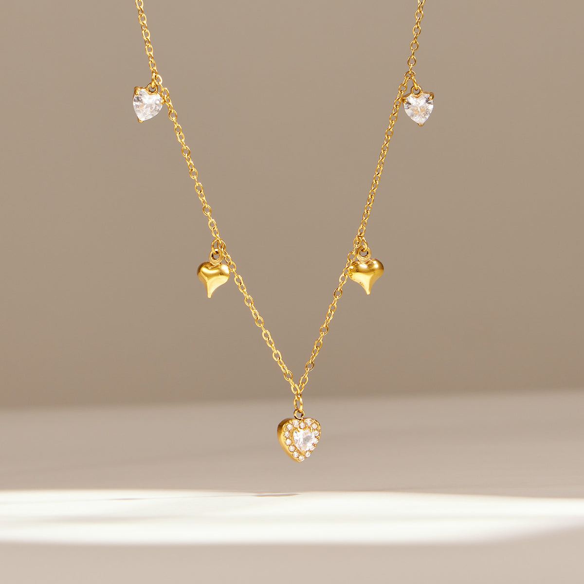 Delicate gold zircon charm necklace with central drop pendant displayed on neutral background