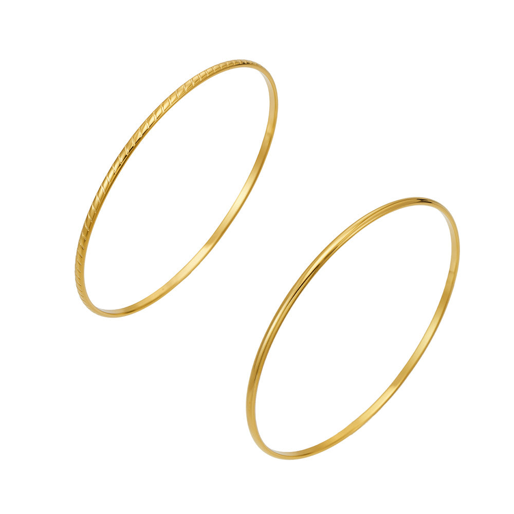 Two slim gold-tone stainless steel stackable bangles in smooth and textured finishes