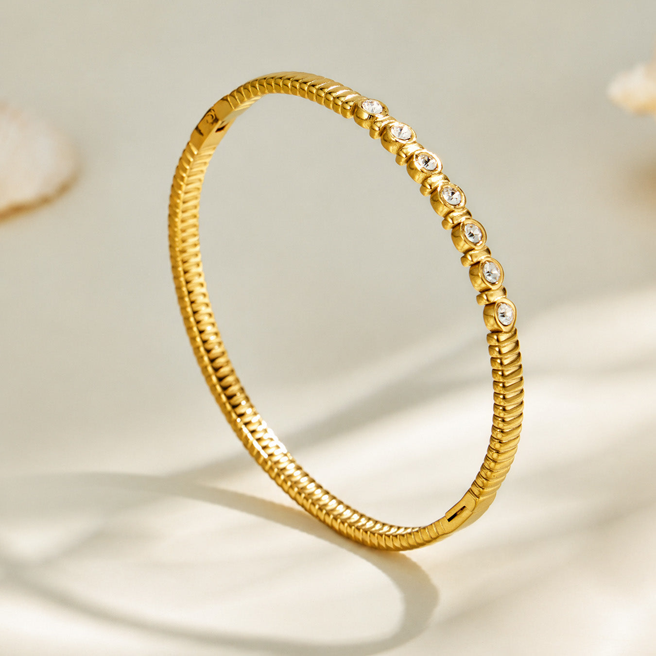 Slim gold zircon bangle displayed upright with decorative stone details