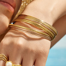 Close-up of a model wearing slim gold and rose gold-tone stackable bangles