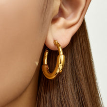 Close-up of smooth gold C-shaped hoop earrings worn on the ear