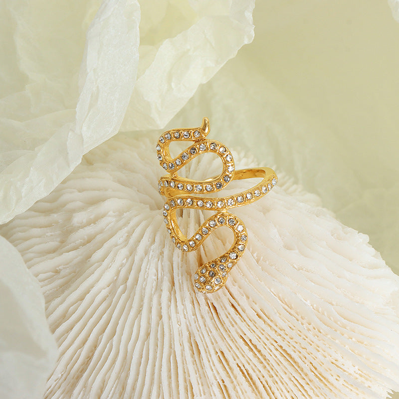 Gold snake open ring with clear cubic zirconia in a styled flat lay