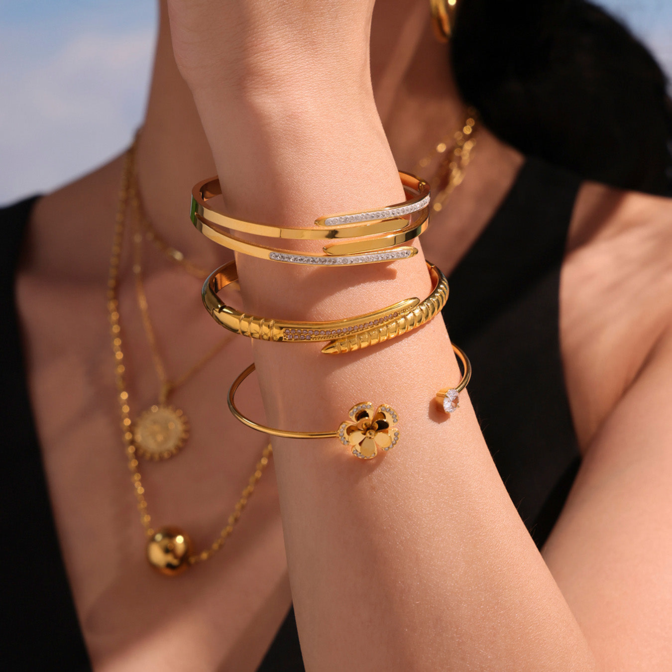 Woman wearing 18K gold plated sparkling zircon starfish flower shell thin open bangle set, layered fashion styling