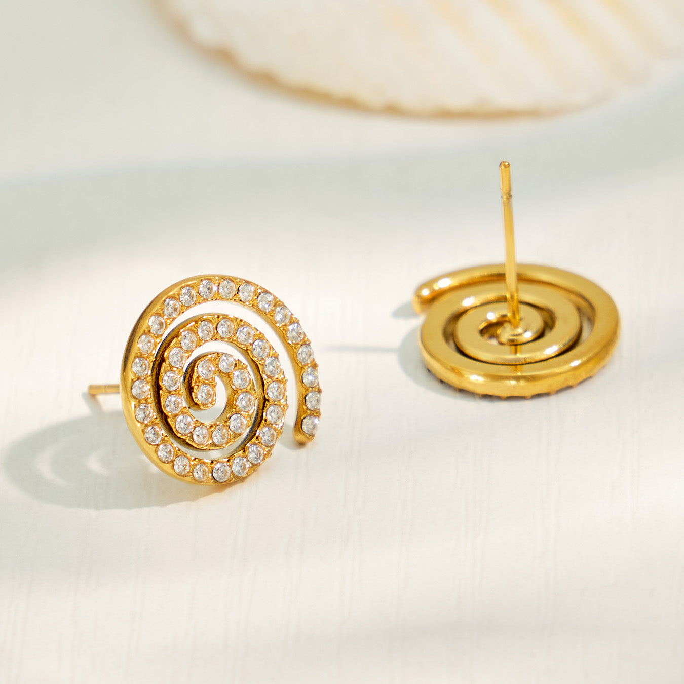 Spiral pavé cubic zirconia stud earrings in a styled flat lay