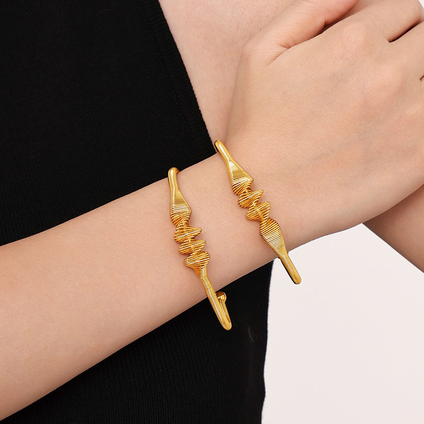 gold plated stainless steel spiral texture bangle, model wearing on wrist