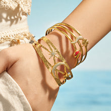 Celestial star moon and chili pepper gold cuff bracelets stacked on a model wrist