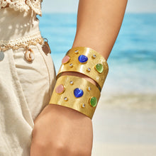 Two stacked gold cat-eye cuff bracelets worn with a white lace outfit