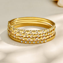 Close-up of stacked gold zircon bangles showing multiple decorative patterns