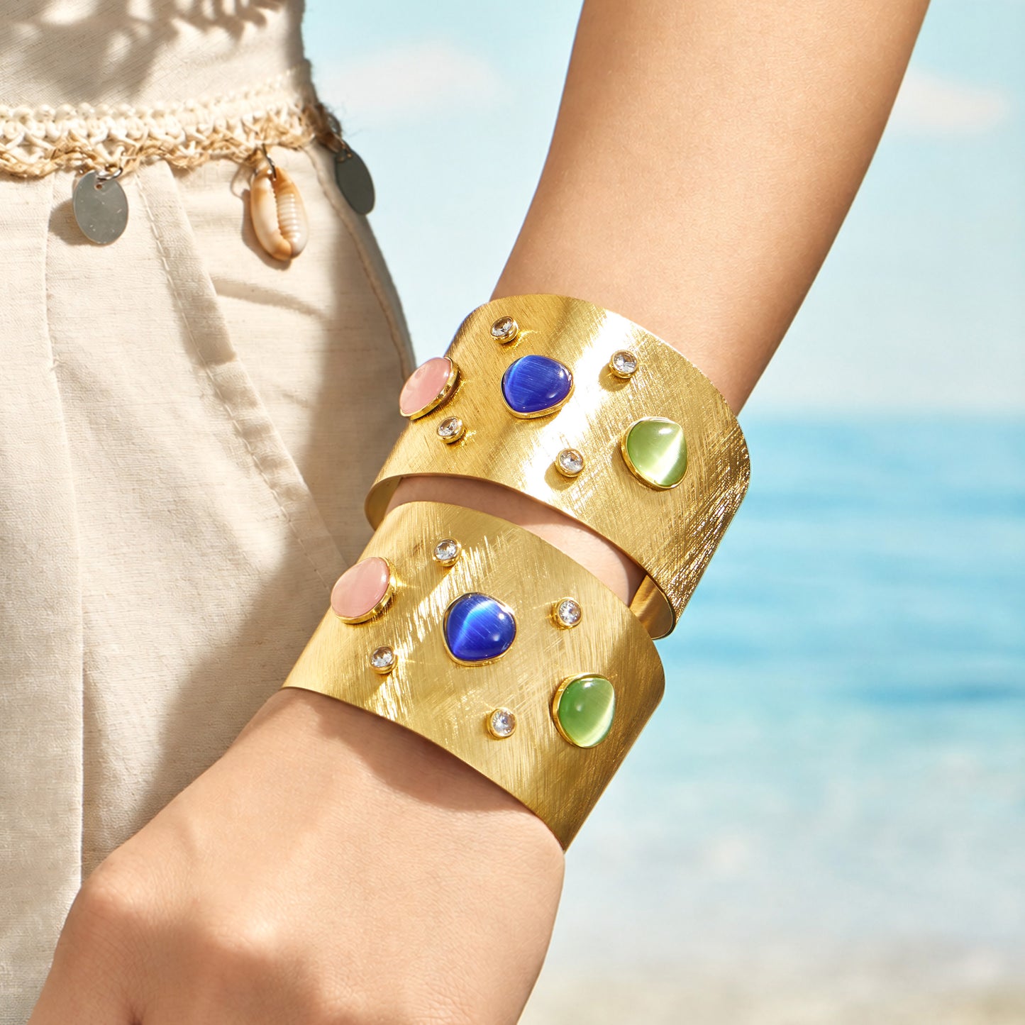 Stacked multicolor gold statement cuff bracelets shown on a model wrist