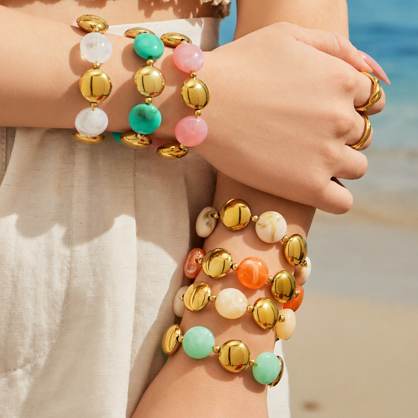 Stacked resin bead bracelets on the arm in colorful tones with gold-tone accents for a trendy layered look.