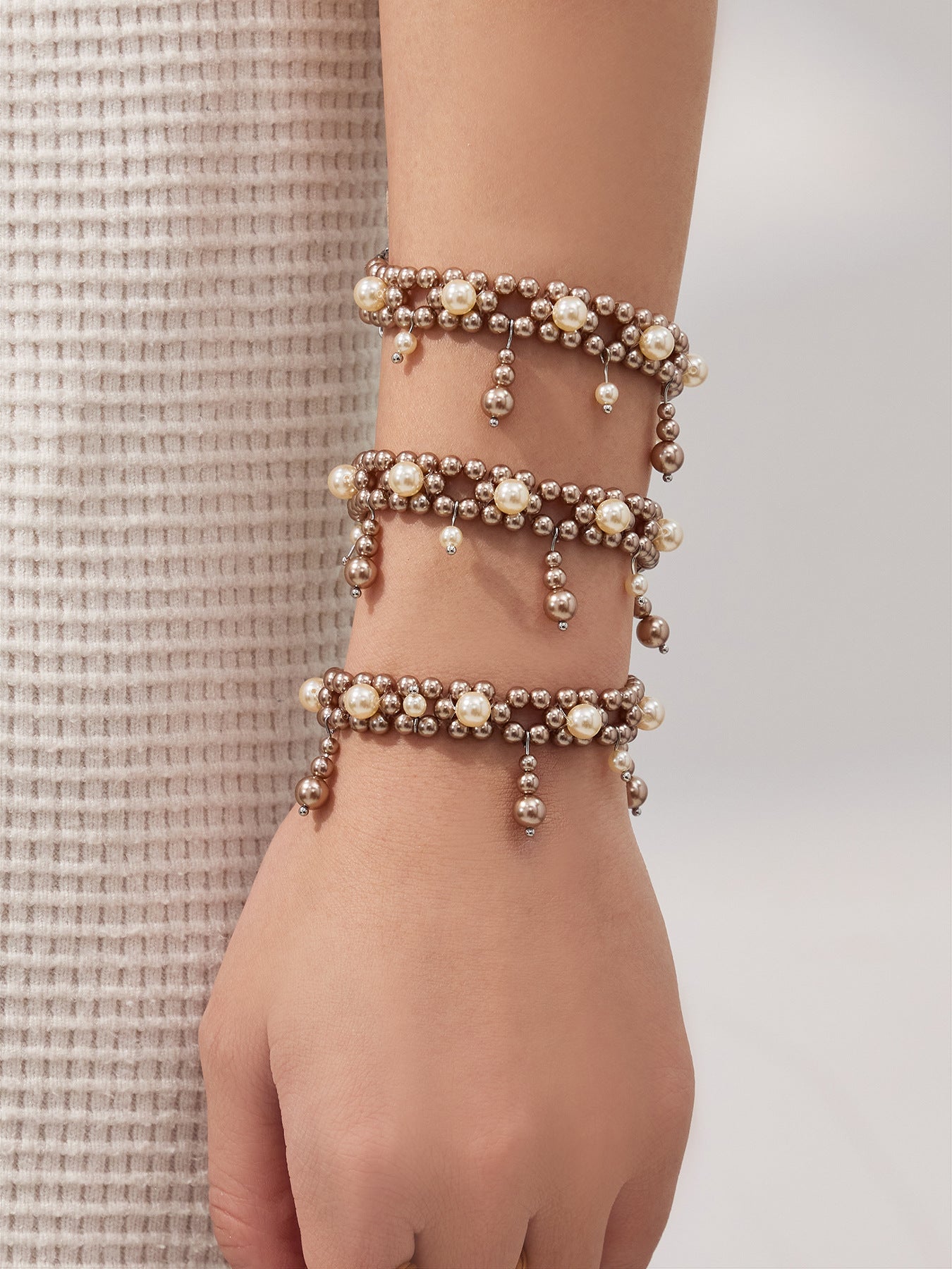 Stacked shell pearl tassel bracelets shown on a model wrist