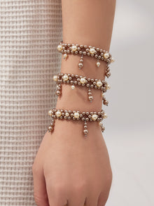Stacked shell pearl tassel bracelets shown on a model wrist