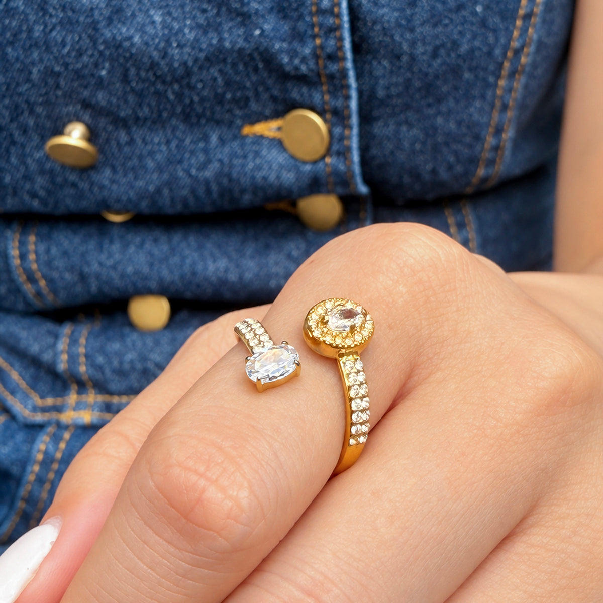 A465 gold-tone two-stone open ring worn on a finger, showing a halo detail and separate clear stone