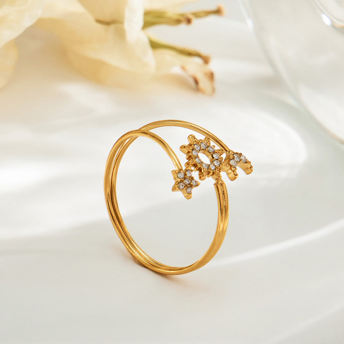 Angled side view of the A466 gold-tone sun, moon and star open ring with layered bands