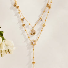 Gold-tone stainless steel cat moon pendant and Y lariat necklaces displayed in layers beside white flowers