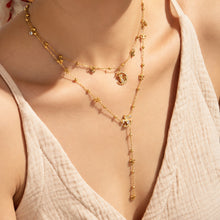 Close-up of layered gold-tone stainless steel cat moon and Y lariat necklaces, with a hand resting near the neck