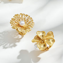 Top view of gold-tone stainless steel flower rings showing openwork petals and a sculpted floral design with faux pearls