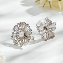 Two silver-tone stainless steel flower rings with white faux pearls, one openwork and one with sculpted petals