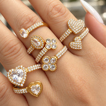 Front hand view of gold-tone heart and flower rings with clear stone accents