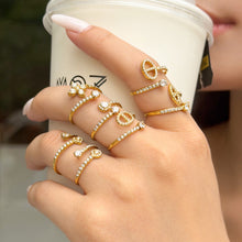 Gold-tone heart, flower and geometric open rings worn across fingers holding a white cup