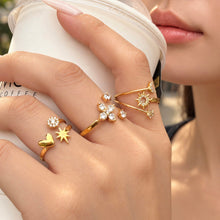 Gold-tone stainless steel open rings worn on a hand holding a white cup