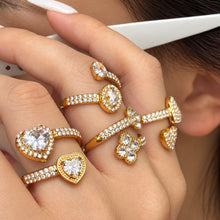 Gold-tone flower, heart and two-stone open rings styled on a hand near the face
