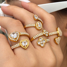 Close-up of gold-tone stainless steel open rings worn together, showing decorative stones and open bands